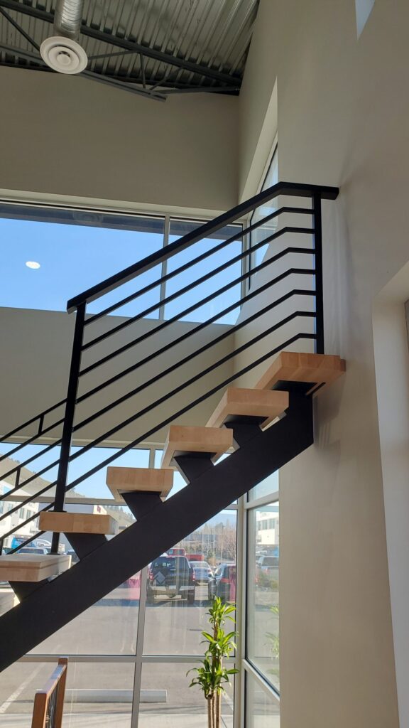 Interior mono stringer stairs with black welded metal railing