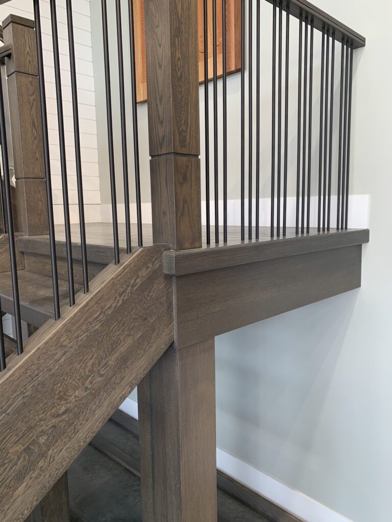 Interior railing with vertical black metal spindles and wooden top rail