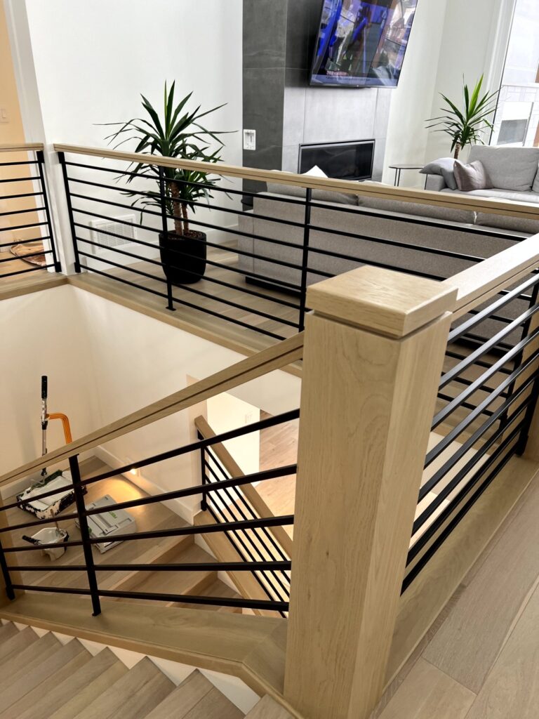 Interior railing with metal spindles and light wood posts and top rail