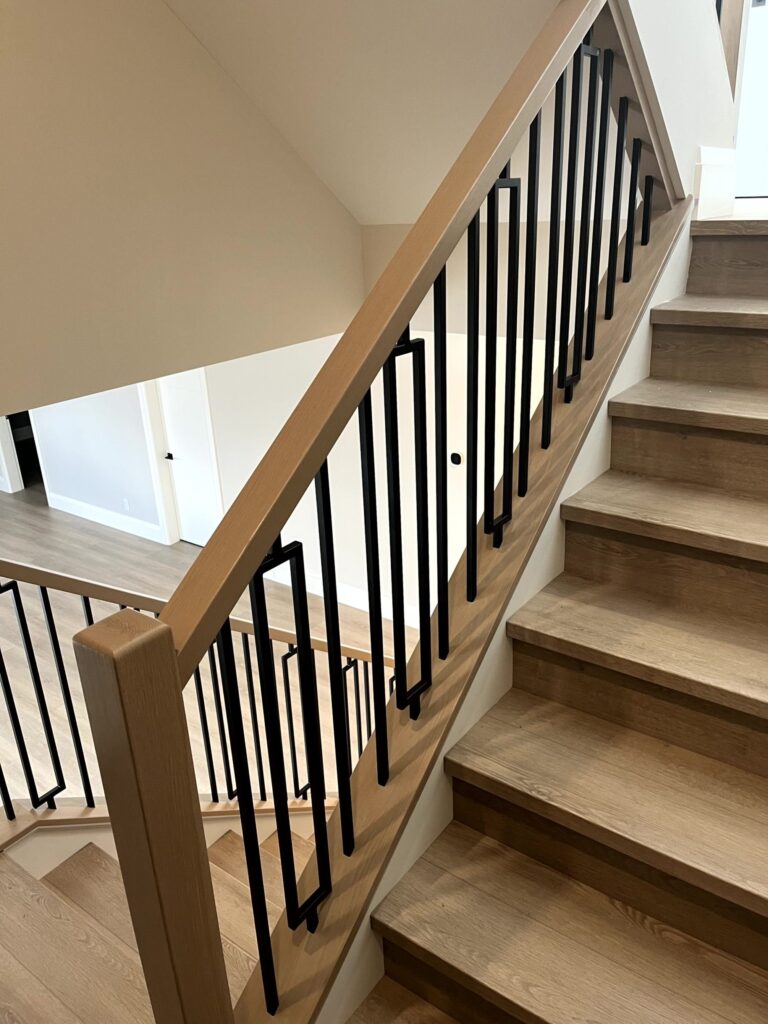 Interior railing with black metal vertical spindles and wooden handrail