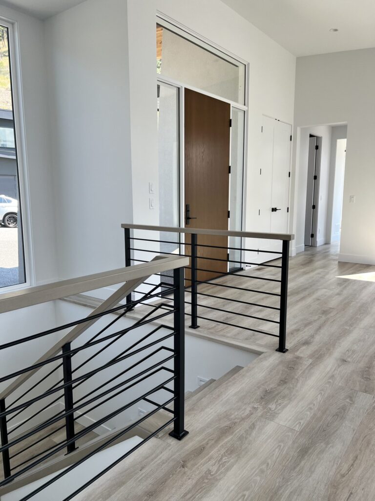 Interior cut out light wood staircase with light wood top rail and black horizontal metal spindles